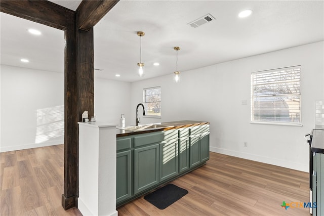 bar with decorative light fixtures, green cabinetry, wood-type flooring, and sink