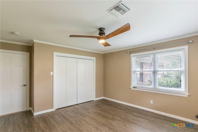unfurnished bedroom with a closet, wood finished floors, visible vents, and baseboards