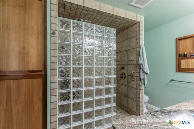 bathroom featuring a tile shower, vanity, and toilet