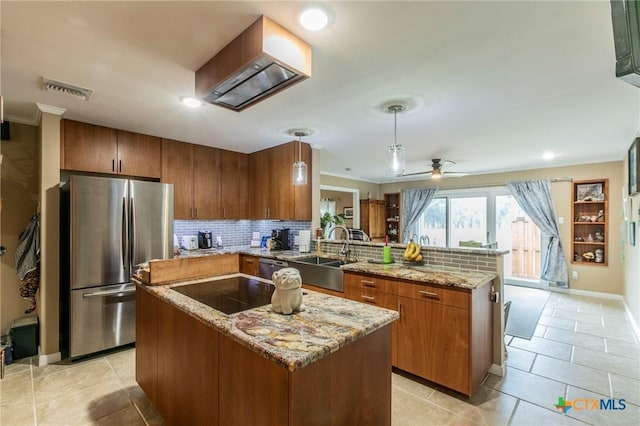 kitchen featuring kitchen peninsula, stainless steel fridge, sink, pendant lighting, and a kitchen island