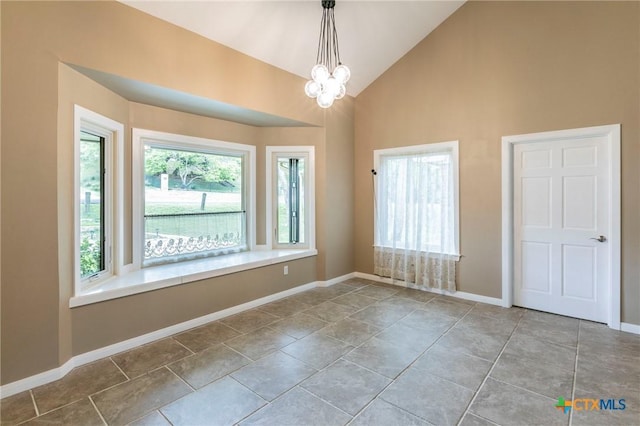 empty room featuring high vaulted ceiling, an inviting chandelier, and baseboards