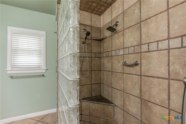 full bath with baseboards, tile patterned flooring, and tiled shower