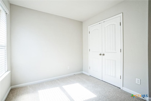 unfurnished bedroom with carpet, baseboards, and a closet