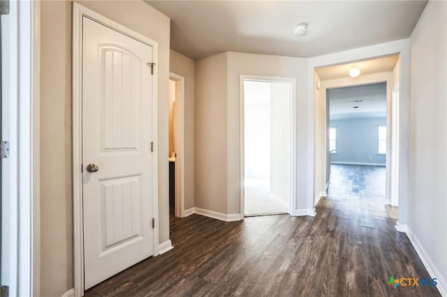 hallway with baseboards and dark wood-style flooring