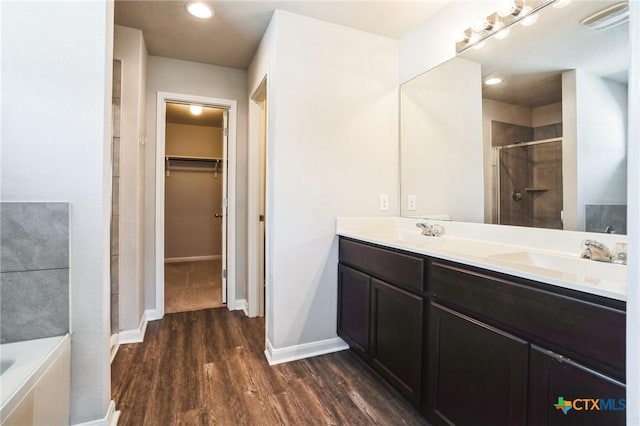 full bath with a garden tub, wood finished floors, a sink, a spacious closet, and a shower stall