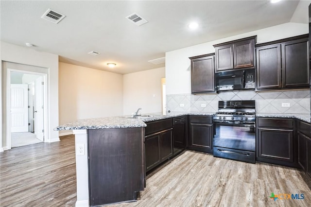 kitchen with light wood finished floors, visible vents, a sink, a peninsula, and black appliances