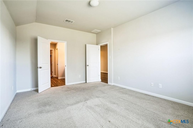 unfurnished bedroom featuring baseboards, visible vents, vaulted ceiling, and carpet flooring