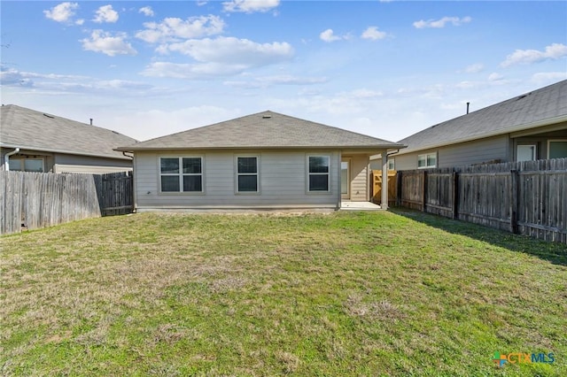 back of house with a fenced backyard and a yard