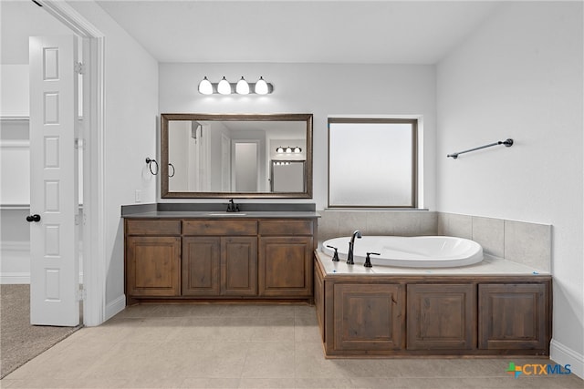 bathroom with a washtub, vanity, and tile patterned floors