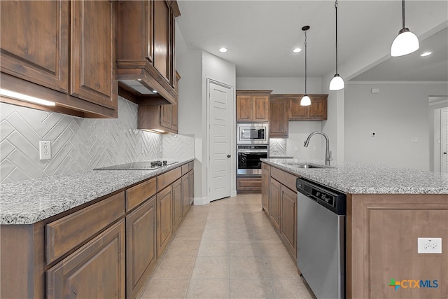 kitchen with tasteful backsplash, stainless steel appliances, decorative light fixtures, sink, and a kitchen island with sink