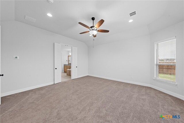 empty room featuring lofted ceiling, light carpet, and ceiling fan