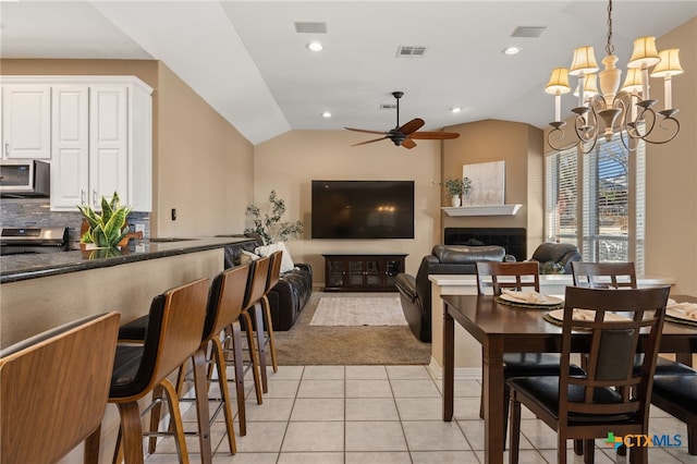 tiled dining space featuring vaulted ceiling and ceiling fan with notable chandelier