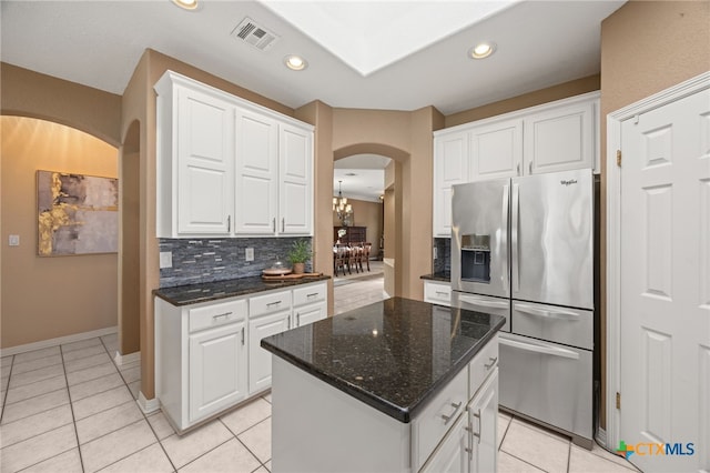 kitchen featuring stainless steel refrigerator with ice dispenser, a center island, decorative backsplash, and white cabinets