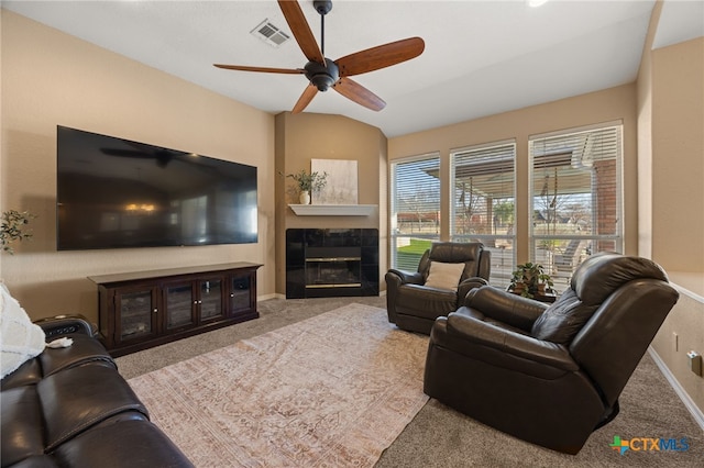 carpeted living room with ceiling fan, vaulted ceiling, and a tile fireplace