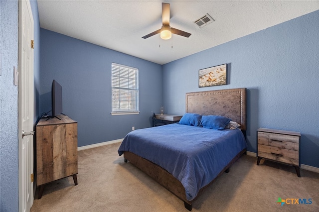 bedroom featuring light carpet, a textured ceiling, and ceiling fan