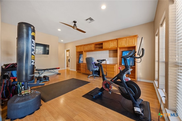 workout area with ceiling fan, built in desk, and light hardwood / wood-style floors