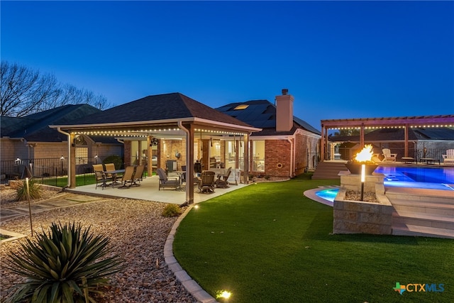 back house at dusk with a patio area, a gazebo, a lawn, an outdoor fire pit, and a fenced in pool