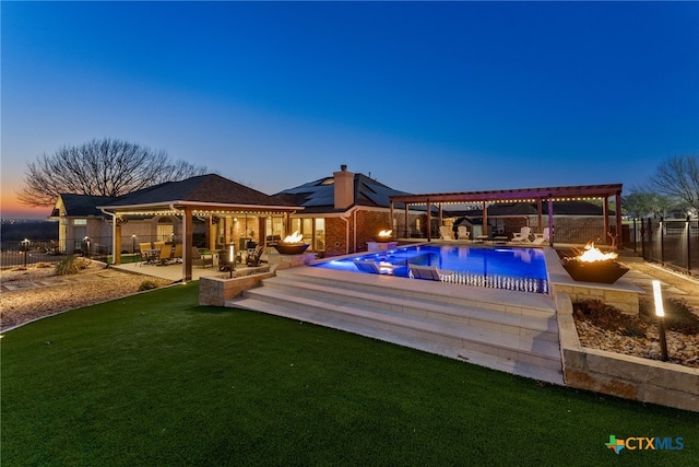 pool at dusk with a lawn, a patio area, and a fire pit