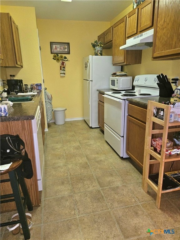 kitchen featuring light tile patterned floors, white appliances, and sink