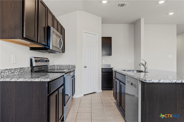 kitchen featuring stainless steel appliances, a center island with sink, dark brown cabinetry, sink, and light tile patterned flooring