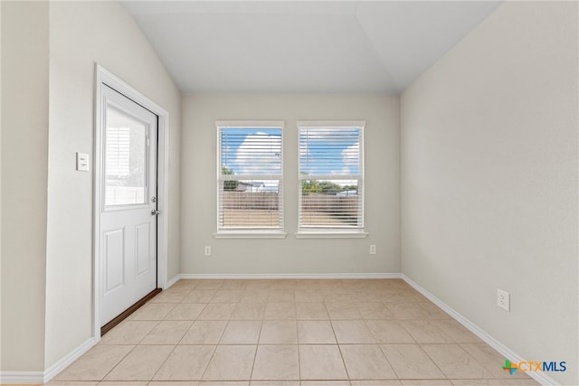 interior space with lofted ceiling and light tile patterned flooring