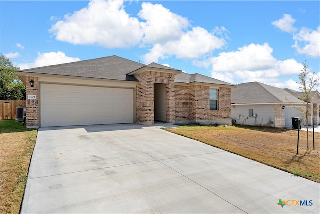 ranch-style house with central air condition unit, a garage, and a front yard