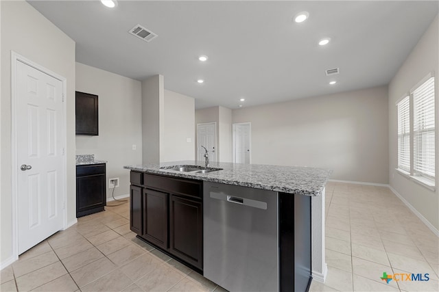 kitchen with light stone counters, light tile patterned flooring, sink, dishwasher, and a kitchen island with sink