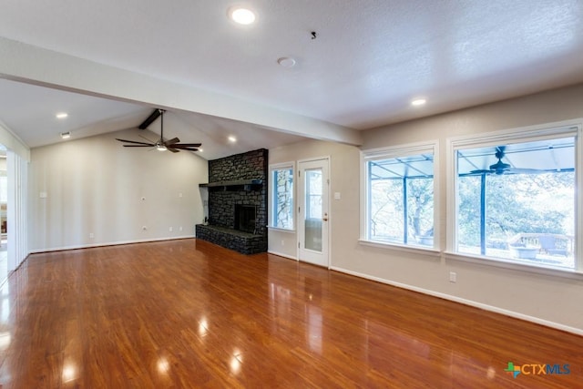 unfurnished living room featuring a large fireplace, ceiling fan, hardwood / wood-style flooring, and lofted ceiling with beams