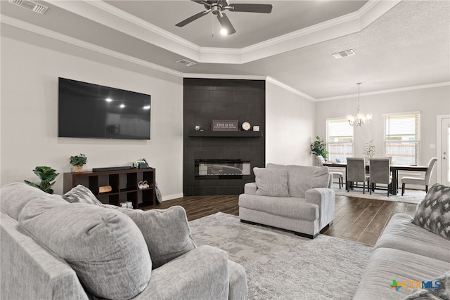 living room featuring hardwood / wood-style flooring, ceiling fan with notable chandelier, crown molding, and a tray ceiling