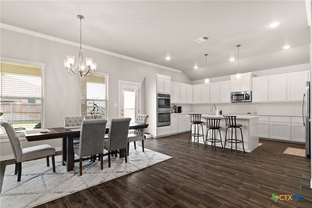 dining area featuring dark hardwood / wood-style floors, vaulted ceiling, ornamental molding, and a notable chandelier