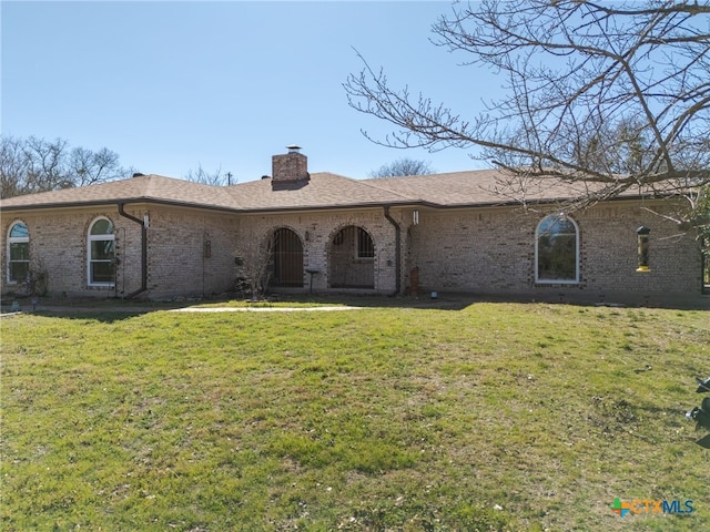 view of front of home featuring brick siding, a chimney, a front lawn, and a shingled roof