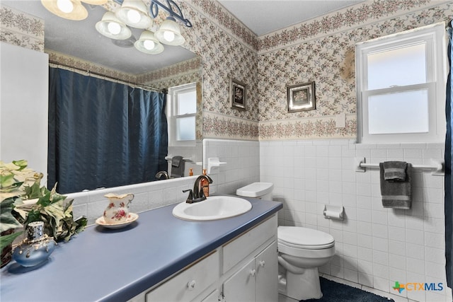 full bath with vanity, a wainscoted wall, wallpapered walls, tile walls, and toilet