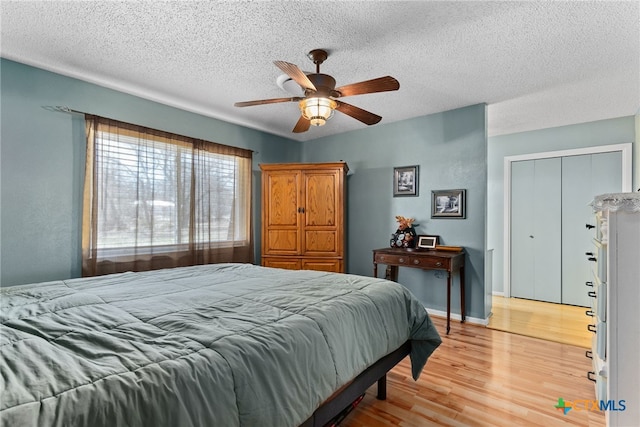 bedroom featuring baseboards, ceiling fan, a textured ceiling, and light wood-style floors