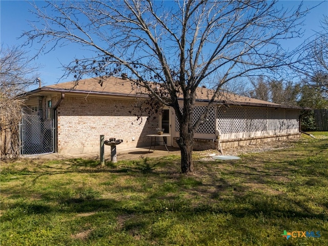 back of house featuring a patio area, fence, a lawn, and brick siding