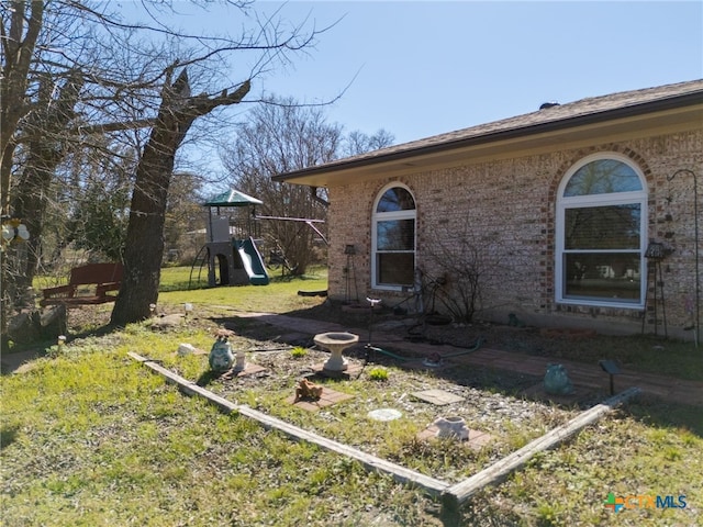 view of home's exterior with brick siding, a lawn, and a playground