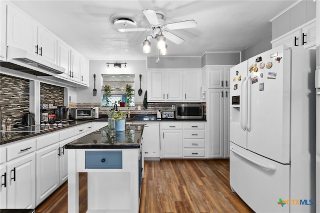 kitchen with dark countertops, white cabinets, white appliances, and a ceiling fan