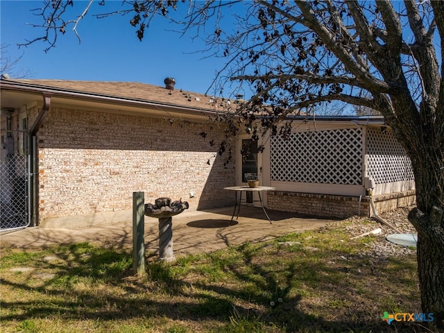 rear view of property featuring a patio area and brick siding