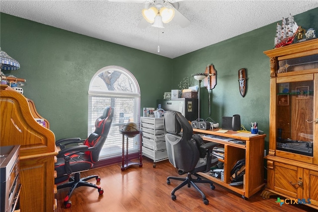 office with a ceiling fan, wood finished floors, a textured wall, and a textured ceiling