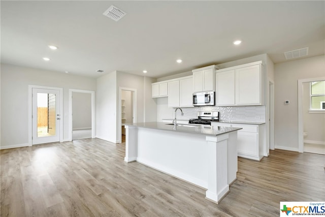 kitchen featuring stainless steel appliances, sink, an island with sink, white cabinets, and light hardwood / wood-style flooring