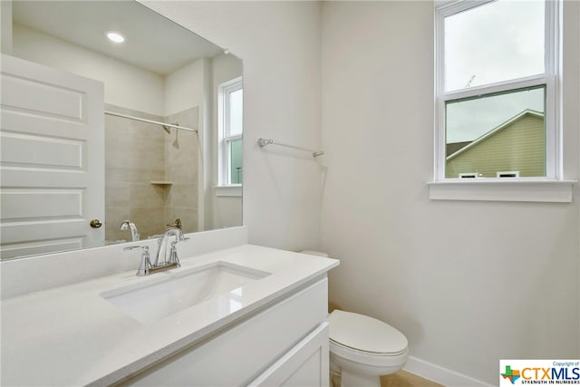 bathroom with a tile shower, vanity, and toilet