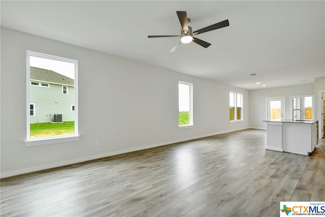 unfurnished living room featuring light wood-type flooring and ceiling fan