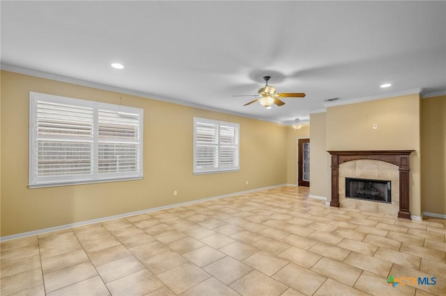 unfurnished living room featuring a tiled fireplace, crown molding, and ceiling fan