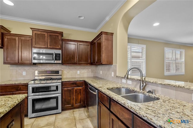 kitchen featuring light stone counters, appliances with stainless steel finishes, crown molding, and sink