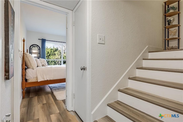 staircase featuring a textured wall and wood finished floors