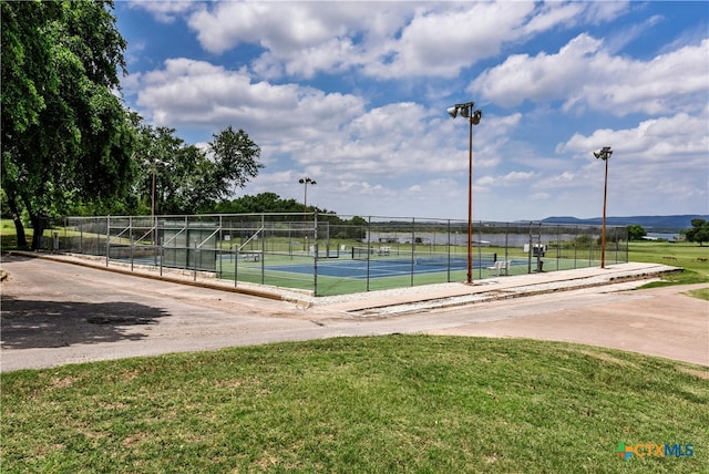 view of tennis court featuring a yard and fence