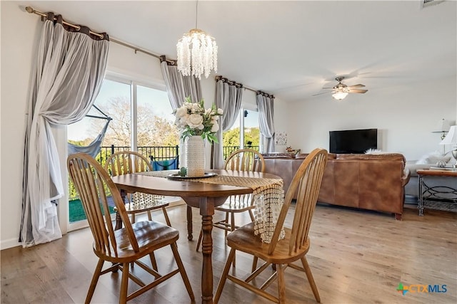 dining space with light wood-type flooring and ceiling fan with notable chandelier