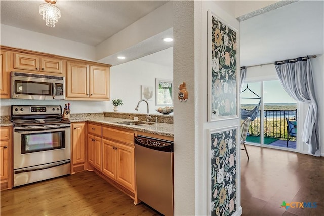 kitchen with light stone countertops, wood finished floors, recessed lighting, a sink, and appliances with stainless steel finishes