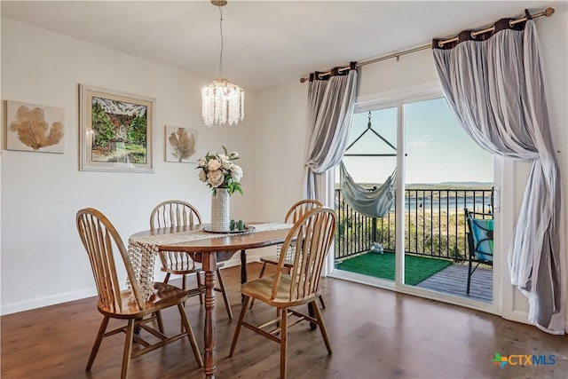 dining space with a wealth of natural light, a notable chandelier, baseboards, and wood finished floors