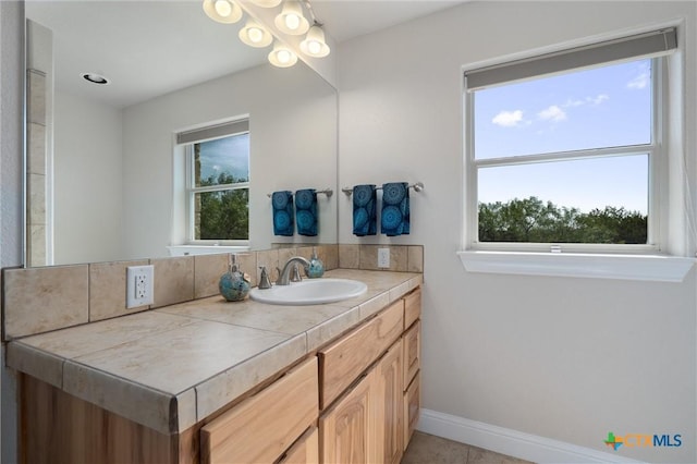 bathroom with vanity, baseboards, and tile patterned floors