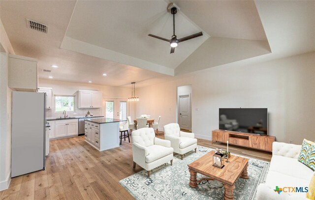 living room featuring light wood-type flooring, sink, vaulted ceiling, and ceiling fan